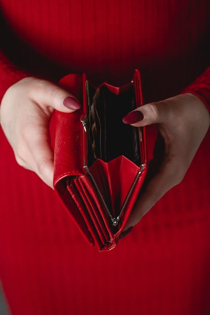 Billetera roja en manos de una mujer con un vestido rojo con manicura roja