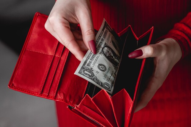 Billetera roja en manos de una mujer con un vestido rojo con manicura roja