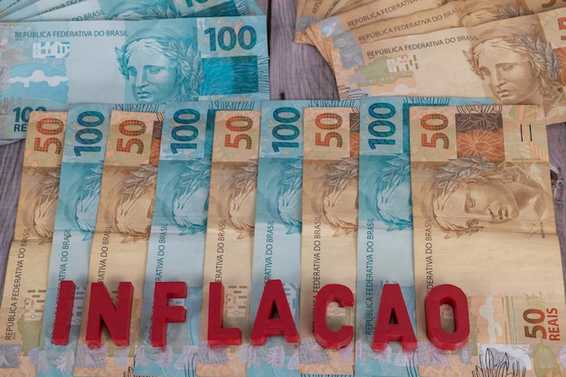 Billetes brasileños Billetes de 50 y 100 reales en la parte inferior con la palabra inflacao en portugués