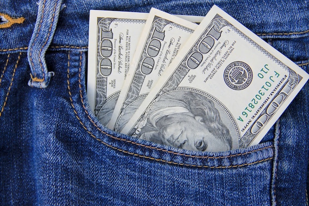 Billetes de dólar americano en el bolsillo de los pantalones vaqueros