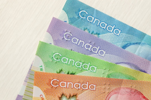 Billetes de dólar canadiense coloridos sobre superficie de madera