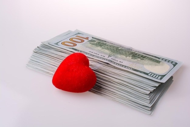 Billetes de dólar estadounidense al lado de un objeto en forma de corazón de color rojo