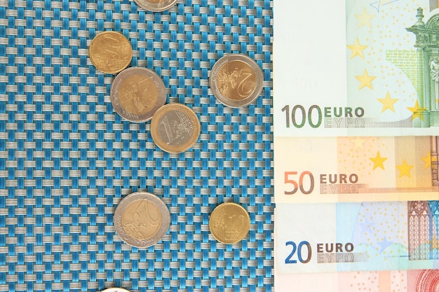 Foto billetes en euros y céntimos de euro sobre fondo azul.