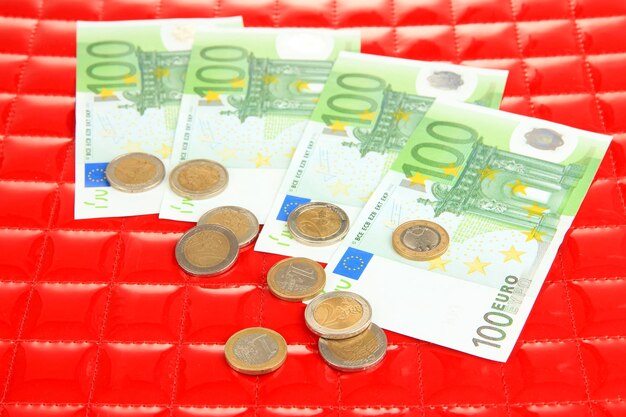 Foto billetes en euros y céntimos de euro sobre fondo rojo.