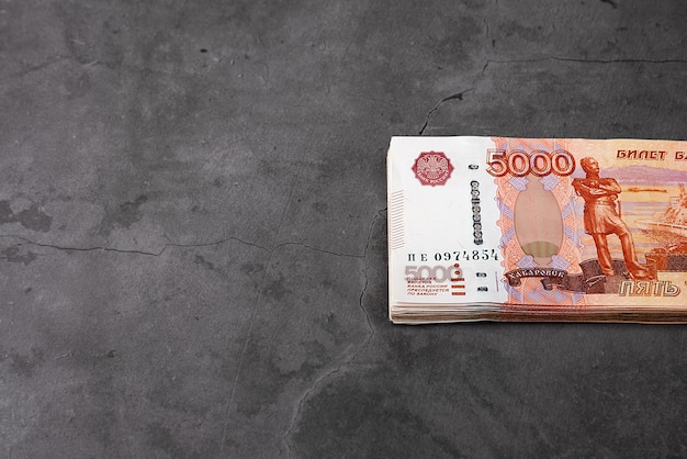 Billetes rusos en efectivo de cinco mil rublos, el paquete cuelga sobre un fondo gris.
