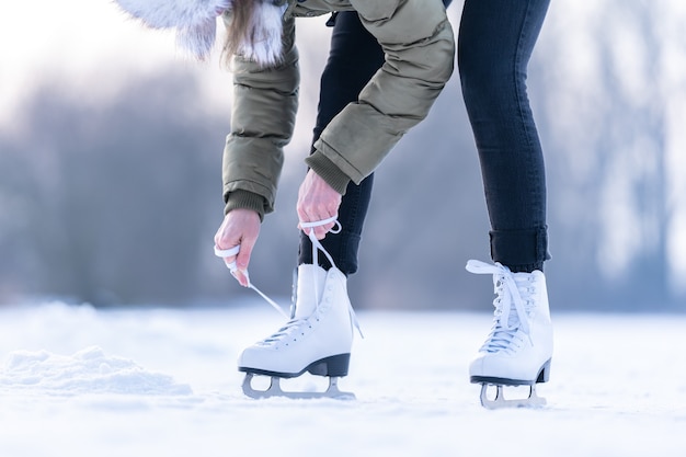 Binden der Schnürsenkel von Winterschlittschuhen auf einem zugefrorenen See, Eislaufen