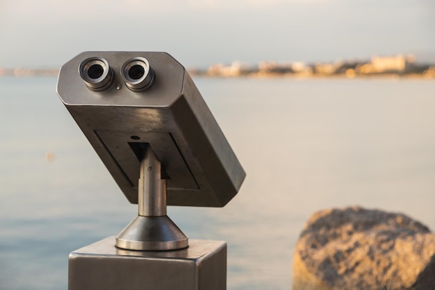 Foto binóculos de metal em close para uso público com vista para o belo porto e o mar