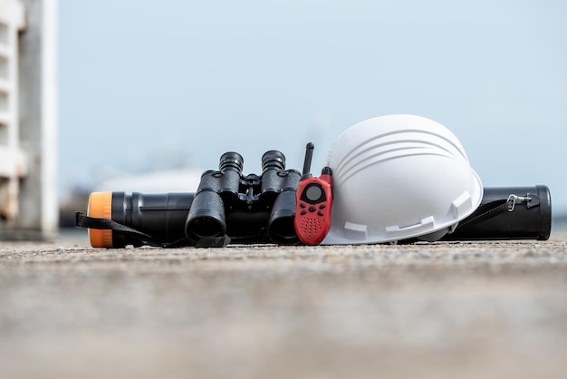 Foto binóculos de rádio walkie talkie de capacete branco e um cilindro de planta colocado no chão