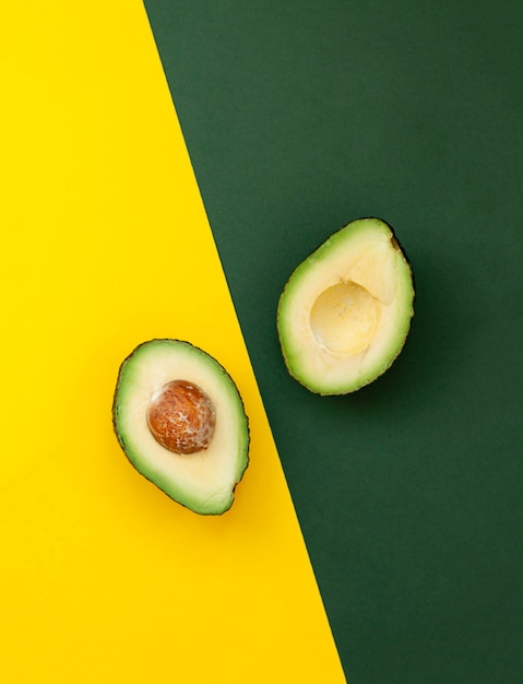 Foto bio-avocado mit samen-avocado-hälften und ganzen früchten auf gelbem und grünem hintergrund