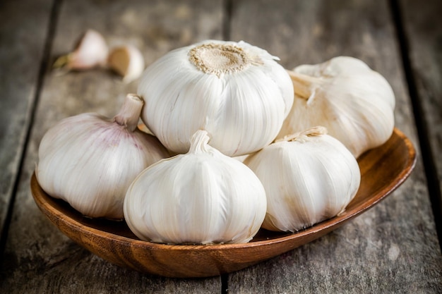 Bio-Knoblauch in der Schüssel auf einem rustikalen Holztisch