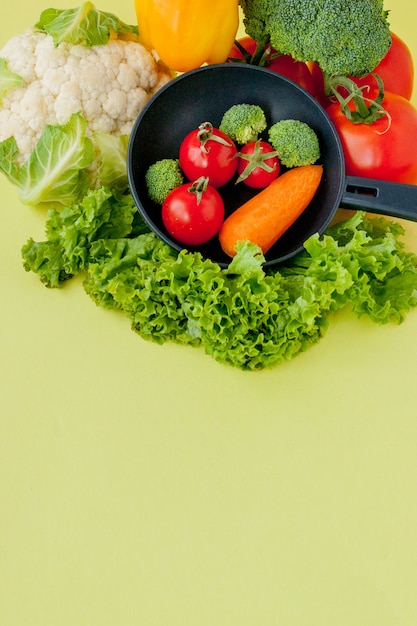 Bio-Lebensmittel. Gesundes Gemüse mit Brokkoli, Kopfsalat, roter und gelber Gemüsepaprika, Gurke auf einer schwarzen Bratpfanne