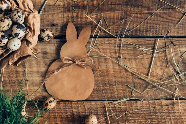 Bio Ostern. Draufsicht auf Wachteleier in zerknittertem braunem Papier und Esterhase, die auf rustikalem Holztisch liegen lying