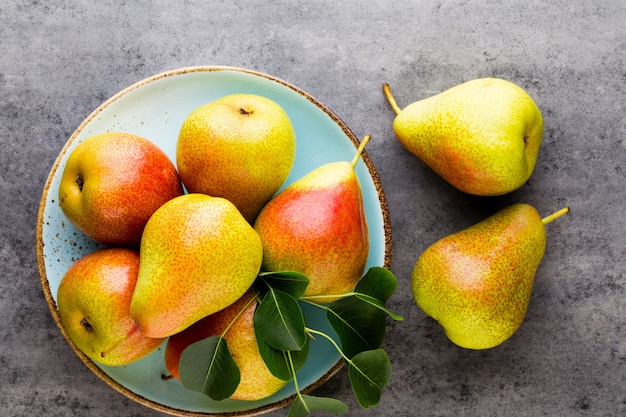 Bio pêra fresca com folhas no prato. mesa de pedra cinza.