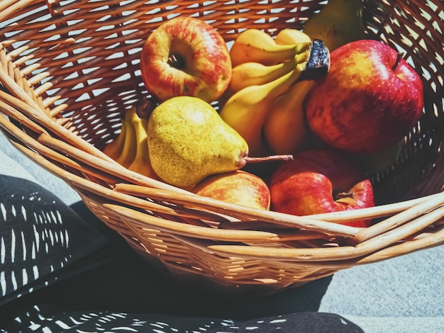 Bio-Äpfel, Birnen und Bananen auf rustikal in einem Weidenkorb