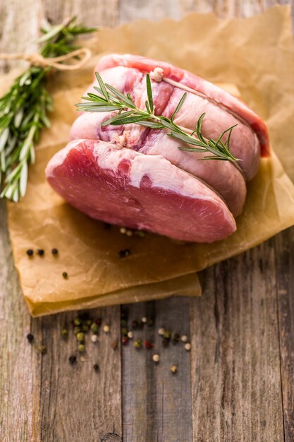 Bio-Schweinslöwenbraten mit Rosmarin auf Holzbauerntisch.