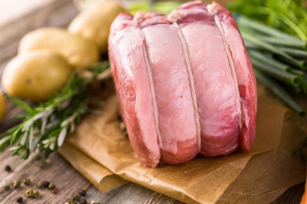 Bio-Schweinslöwenbraten mit Rosmarin auf Holzbauerntisch.