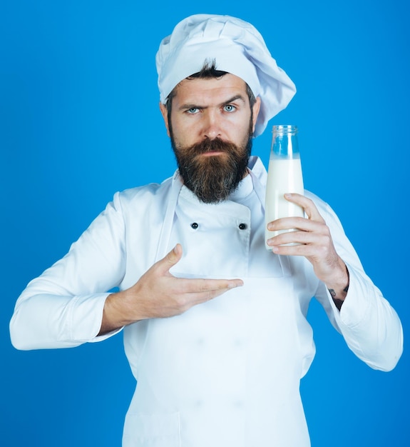 Bio-Zutaten, Proteindiät, nahrhafte Laktose, gesunde Ernährung, Milchproduktkonzept - männlicher Koch hält Flaschenmilch. Seriöser Koch oder Konditor zeigt mit der Hand auf frische Milch für die Zubereitung von Desserts