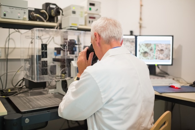 Biochemiker, der großes Mikroskop und Computer verwendet