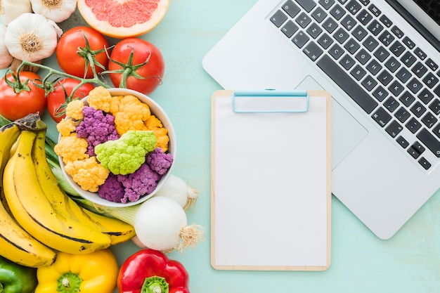 Biokost mit leerem Klemmbrett und Laptop über dem Schreibtisch