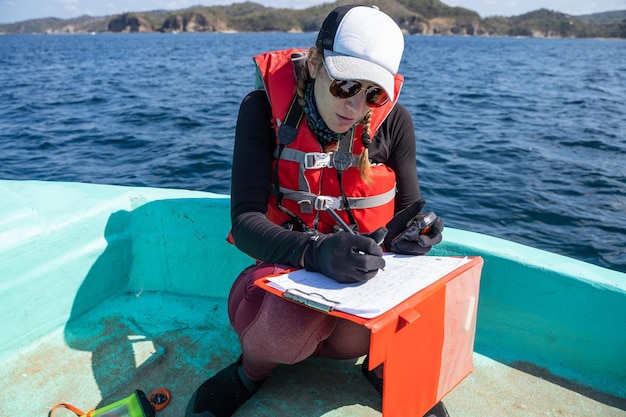 Biólogo marinho equipado escrevendo notas em um barco