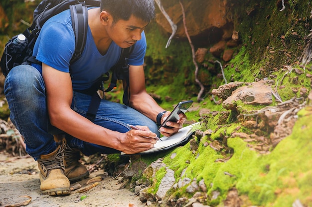 Foto biólogo ou botânico registrando informações sobre pequenas plantas tropicais na floresta.