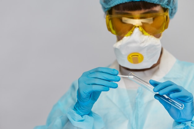 Bioquímico em traje protetor retirando amostras do tubo de ensaio isolado em cinza, copie o espaço