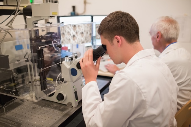 Bioquímico y estudiante mirando imágenes microscópicas en la computadora