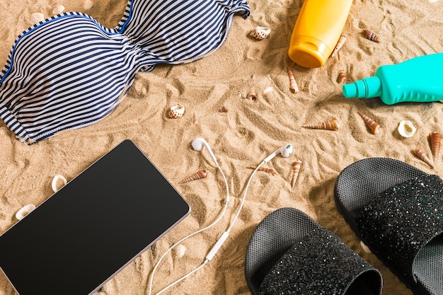 Biquíni de verão e acessórios elegantes conjunto de praia, biquíni de praia e areia do mar como fundo, vista de cima, conceito