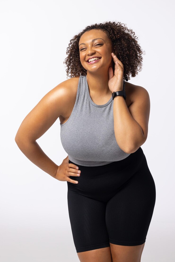 Foto biracial plusize jovem modelo feminina ri tocando seu rosto fundo branco
