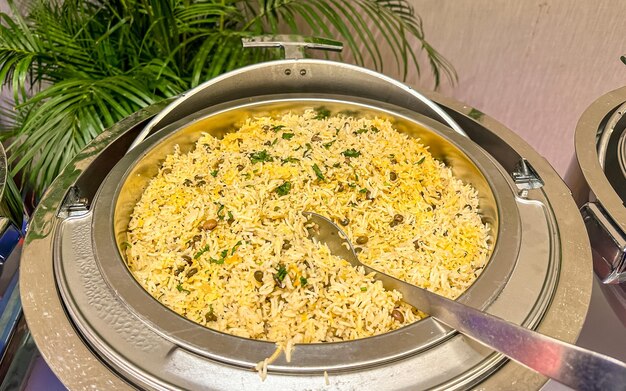 Biriyani árabe en una olla de acero inoxidable con cuchara y tenedor