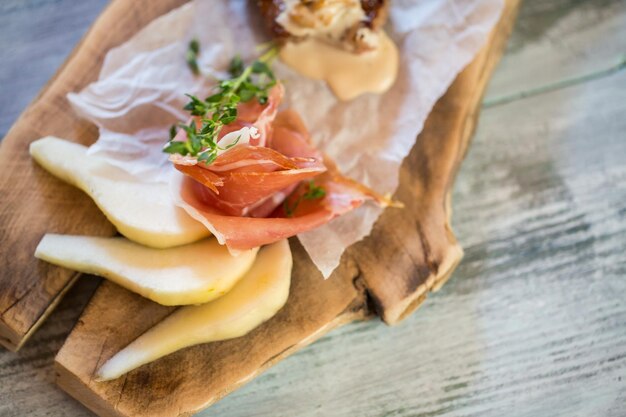 Birnenscheiben an Bord. Speck mit grünem Kraut. Gericht weckt den Appetit. Dekoration von Rindermedaillons.