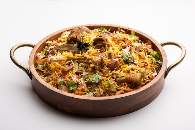 Biryani de cordero indio preparado en arroz basmati servido con salsa de yogur sobre fondo cambiante, enfoque selectivo