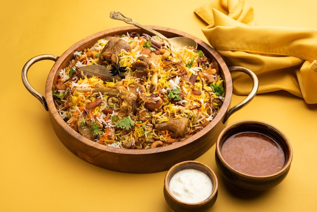 Biryani de cordero indio preparado en arroz basmati servido con salsa de yogur sobre fondo cambiante, enfoque selectivo