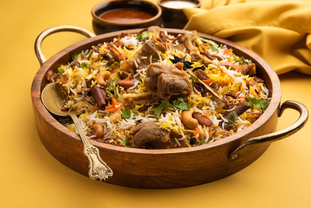 Foto biryani de cordero indio preparado en arroz basmati servido con salsa de yogur sobre fondo cambiante, enfoque selectivo