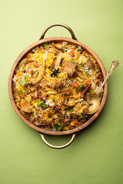 Biryani de cordero indio preparado en arroz basmati servido con salsa de yogur sobre fondo cambiante, enfoque selectivo