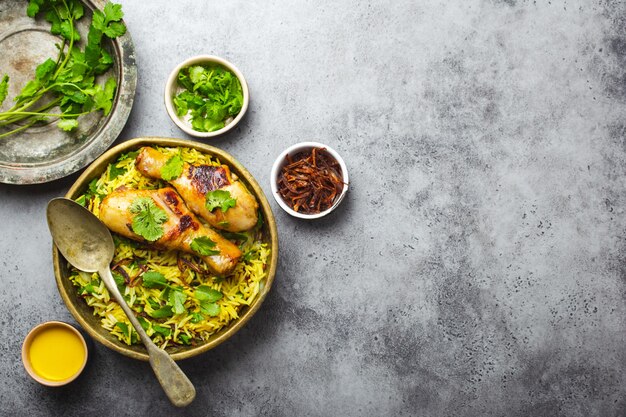 Biryani-Huhn, traditionelles Gericht der indischen Küche, mit Basmatireis, gebratenen Zwiebeln, frischem Koriander in Schüssel auf grauem rustikalem Steinhintergrund. Authentisches indisches Essen, Draufsicht, Nahaufnahme, Platz für Text