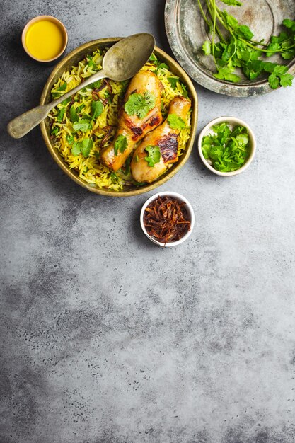 Biryani-Huhn, traditionelles Gericht der indischen Küche, mit Basmatireis, gebratenen Zwiebeln, frischem Koriander in Schüssel auf grauem rustikalem Steinhintergrund. Authentisches indisches Essen, Draufsicht, Nahaufnahme, Platz für Text