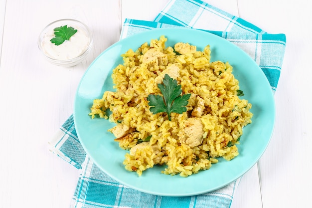 Biryani indiano com frango, iogurte e especiarias no prato na mesa de madeira. Ano Novo, prato de Natal