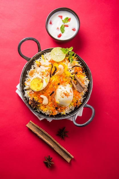 Biryani indio de huevo o arroz anda servido en kadhai o kadai con salsa de yogur, enfoque selectivo