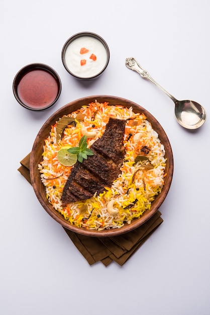 Biryani de pescado o arroz de pescado: receta popular no vegetariana de la India hecha de pescado marinado con especias indias, hierbas frescas y cocido con arroz basmati, enfoque selectivo