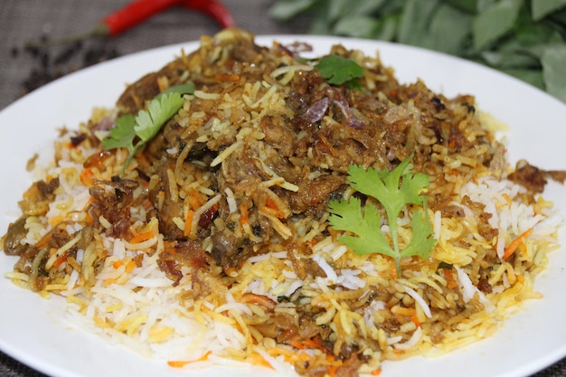 Biryani de pollo picante servido en un plato aislado en una vista lateral de fondo de madera