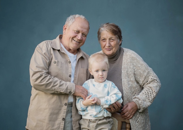 Bisabuela y bisabuelo con bisnieto sobre fondo azul.