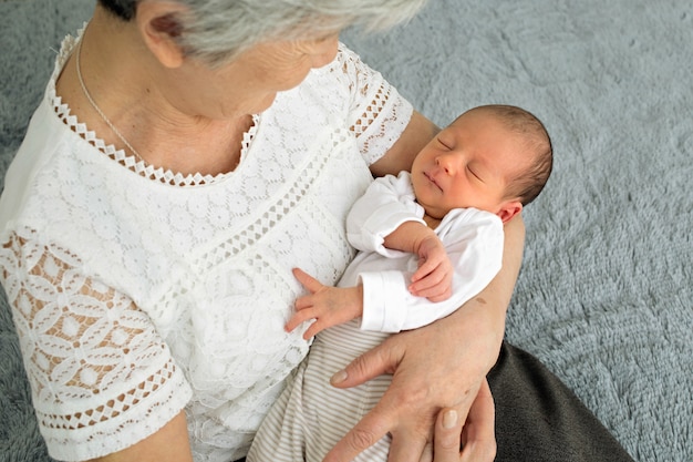 Foto la bisabuela sostiene a una bisnieta recién nacida en sus brazos