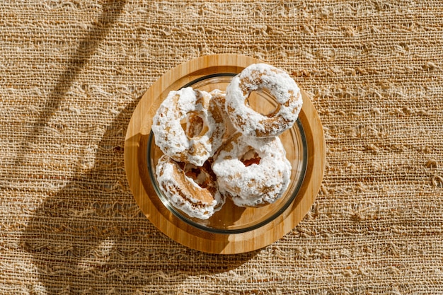 Biscoito amanteigado com açúcar de confeiteiro por cima em um recipiente de vidro transparente. luz forte com sombras nítidas. vista do topo. foco seletivo.