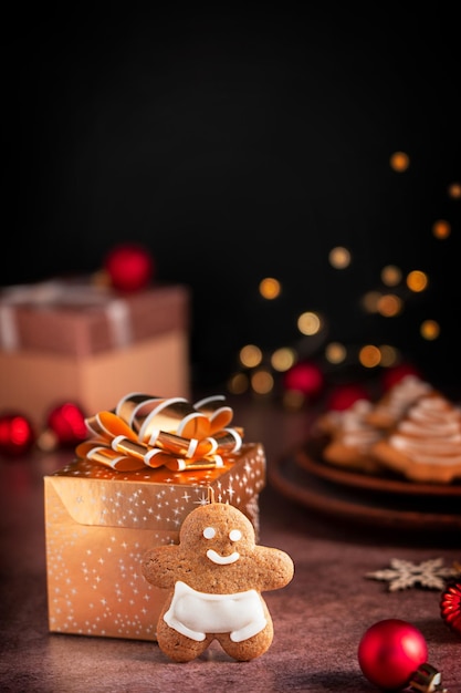 Biscoito caseiro de gengibre servido na mesa com caixa de presente dourada de natal e luzes bokeh