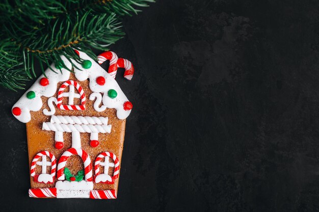 Biscoito de casa de gengibre Biscoito de casa de gengibre caseiro com galho de árvore de abeto de natal em fundo de pedra escuro Vista superior com espaço de cópia Padaria de natal Biscoitos tradicionais festivos