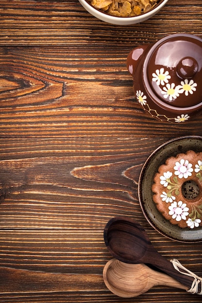 Biscoito de gengibre caseiro, tigela com flocos de milho e pote de mel no fundo de madeira