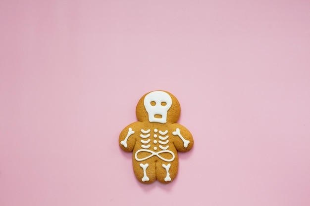 Biscoito de gengibre de esqueleto em um fundo rosa biscoitos doces ou travessuras de halloween