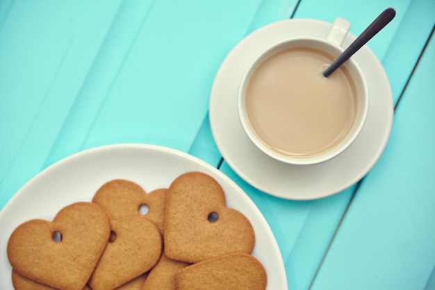 Biscoito de gengibre em forma de coração na placa cinza com vista superior da xícara de café mesa de madeira velha