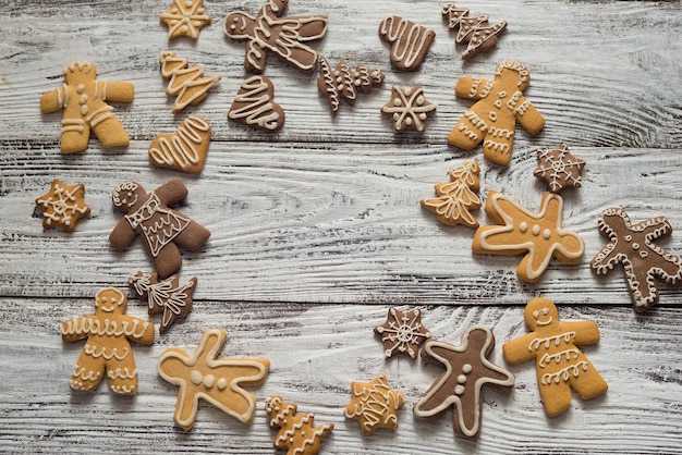 Biscoito de Natal e doces na madeira, vista superior dos alimentos. Presentes com papel artesanal. Texto.